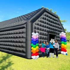 three people standing in front of an inflatable house with balloons on the side