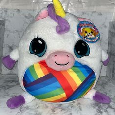 a stuffed animal with a rainbow ball in it's mouth on a marble surface