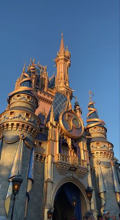 a castle with a giant clock on it's side and people standing in front