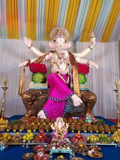 the statue of lord ganesh is surrounded by fruits and other decorative items on display