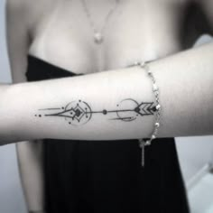 a woman's arm with an arrow tattoo on it