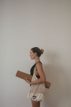 a woman is carrying a large piece of paper in her hand while standing against a white wall