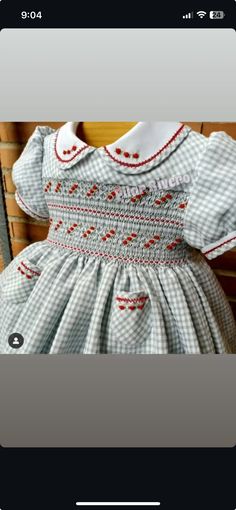 a baby's smocked dress is displayed on a cell phone, with the screen showing