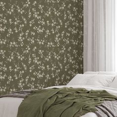 a bed sitting next to a green wallpaper covered in white and pink flowers on it