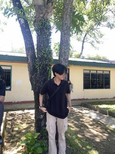 a woman standing next to a tree in front of a building