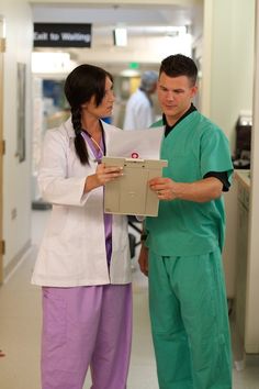 a man and woman in scrubs standing next to each other holding a piece of paper