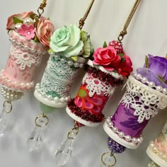 several different colored vases with flowers in them hanging from chains on a white wall