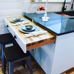 a kitchen table with two plates on it and three stools in front of it