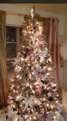 a white christmas tree with pink and silver ornaments