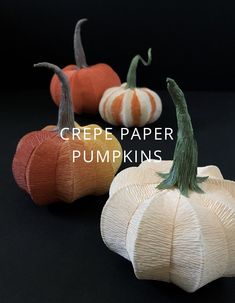 three small pumpkins sitting next to each other on a black surface with the words crepe paper pumpkins