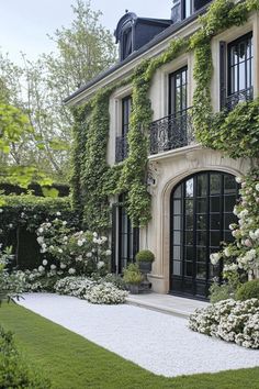 a large house with lots of windows and plants on the front door, surrounded by greenery