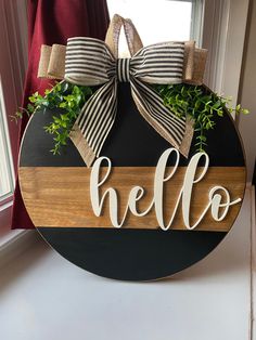 a wooden sign with the word hello painted on it and a bow tied to it