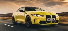 a yellow sports car driving down the road with dark clouds in the sky behind it