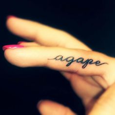 a person's hand with a small tattoo on the middle finger that says age