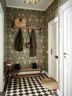 an entryway with two coats hanging on the wall and a checkered floor in front of it