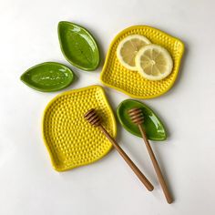 three yellow plates with green leaves and two lemon slices on them, one has a honey comb in the middle