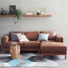 a living room with a brown leather couch and wooden shelves on the wall above it