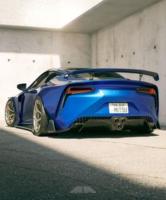 a blue sports car parked in front of a white wall with the license plate on it