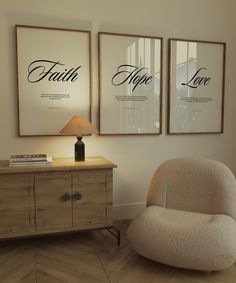 two framed posters on the wall above a dresser with a chair in front of it