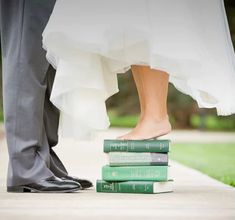 the bride and groom are standing next to each other with their feet on some books