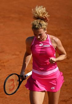 a female tennis player is holding her racket in one hand and looking down at the ground