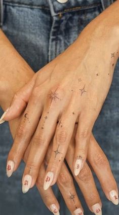 a woman's hand with stars and numbers tattooed on her left thumb, holding onto the wrist