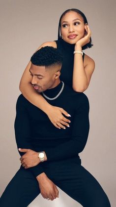 a man holding a woman on his back while she is wearing a black dress and pearls necklace