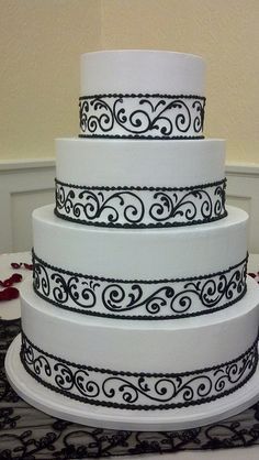 a three tiered white cake with black swirl designs on it's sides and bottom