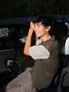 a man sitting in the drivers seat of a golf cart at night with his hand on his head