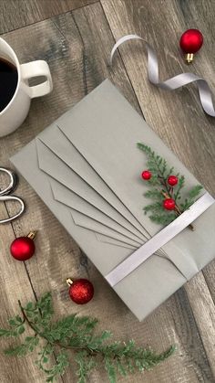 a christmas card and coffee cup on a wooden table next to some scissors, ribbon and ornaments