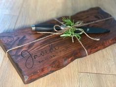 a wooden cutting board with a knife and some string tied around it on the floor