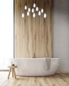 a white bath tub sitting next to a wooden wall with five lights hanging from it