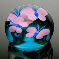 a glass vase with pink and blue flowers in it on a black tableclothed surface