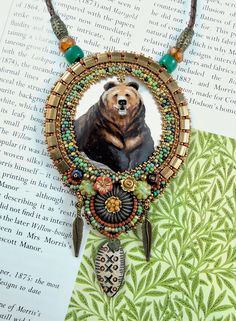 a bear is shown in the center of a necklace with feathers and beads on it