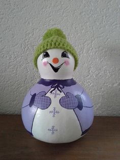 a snowman with a green hat on top of it's head sitting on a table