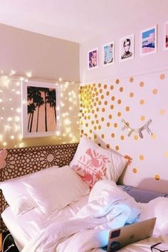 an unmade bed with white sheets and lights on the headboard is shown in this bedroom