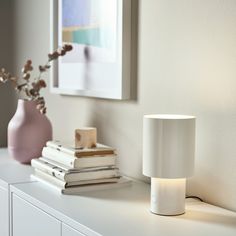 a white lamp sitting on top of a table next to books