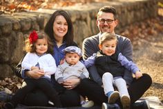 a family sitting on the ground in front of some rocks