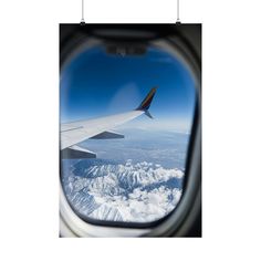 an airplane window looking out at the mountains and clouds from inside another plane's wing