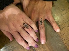 two people with matching rings on their fingers and one has a bow tattoo on it's ring finger