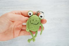 a crocheted frog keychain is being held in someone's hand