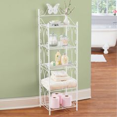 a white shelf with towels and other items on it next to a green wall in a bathroom