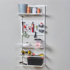 a white shelving unit with tools on the top and shelves below it, against a gray wall