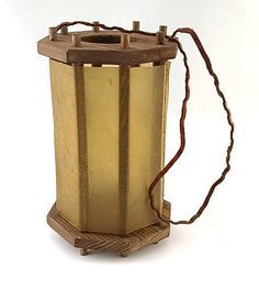 an old fashioned lantern is sitting on a white surface with a string attached to it