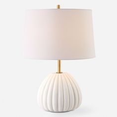 a white table lamp with a gold base and a light shade on the top of it