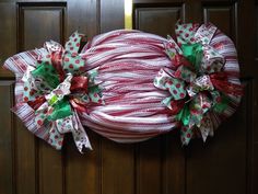 a red and white wreath on the front door with green and red bowknots