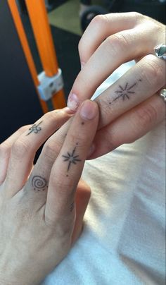 two people with tattoos on their fingers and one holding the other's hand in front of them