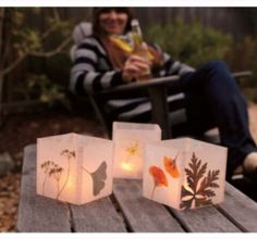 a woman sitting on a bench next to three paper bags with flowers and leaves in them