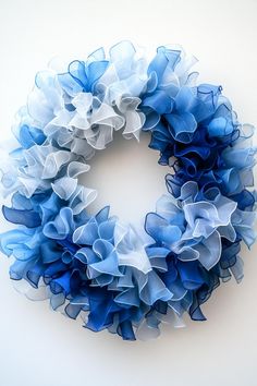 a blue and white wreath with ruffles hanging from it's sides on a wall