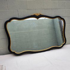 a mirror sitting on top of a table next to a brick wall and white sheet